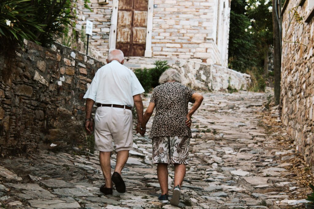 Elderly Couple walking on cobblestone, holding hands