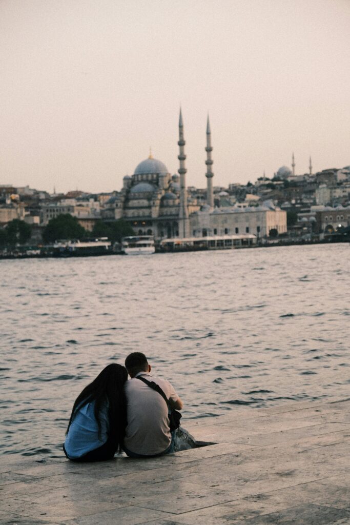 Couple sitting by the water, having a tender moment 